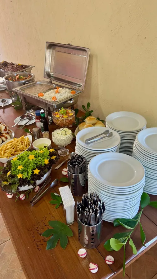 Mesa de buffet montada com churrasco, saladas e acompanhamentos para evento do Dener