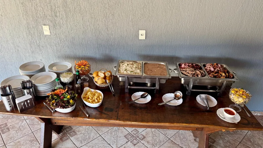 Buffet completo com pratos brancos, talheres e guarnições coloridas