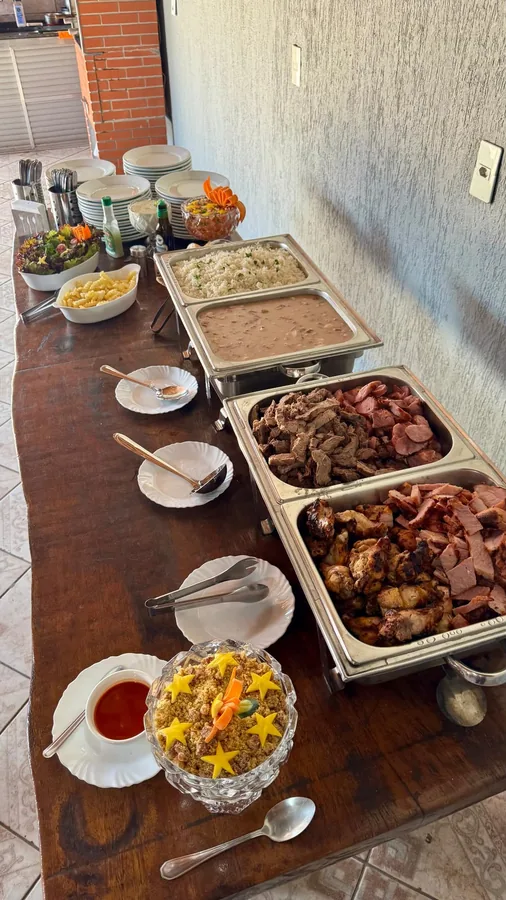 Mesa de evento com churrasco, batata frita e salada fresca